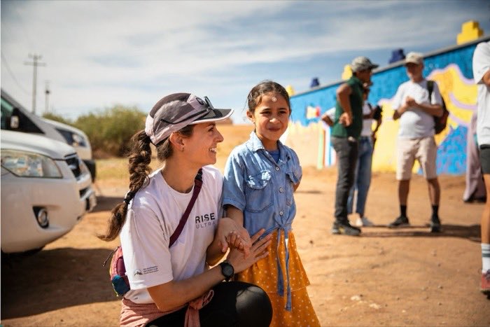 A Rise Ultra runner talking with a young girl during a community visit in the High Atlas